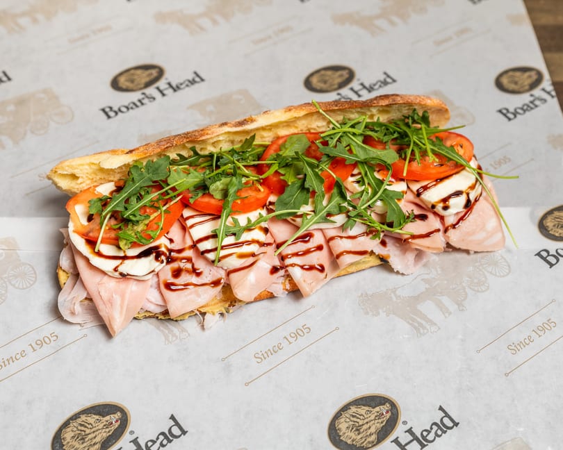 Boar's Head sandwich with mortadella, mozzarella, tomatoes, arugula, and balsamic glaze on a baguette.